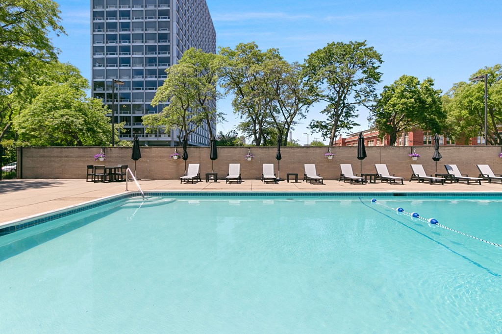 A swimming pool surrounded by trees and chairs at The Pavilion, Detroit, MI
