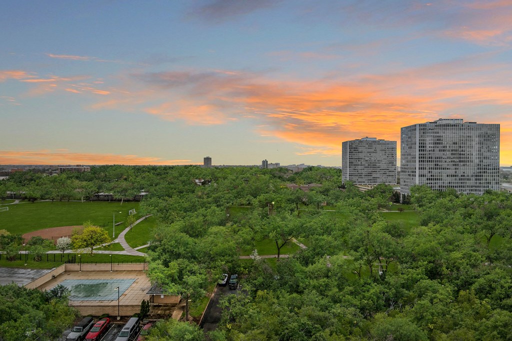 an aerial view of a park with buildings in the background and a colorful sunset in the sky at The Pavilion, Detroit, MI, 48207