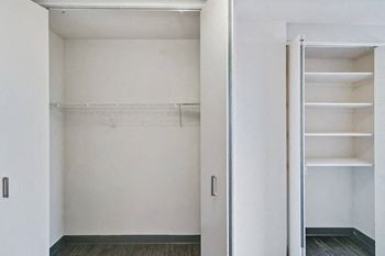 a walk in closet with white walls and a mirrored door
