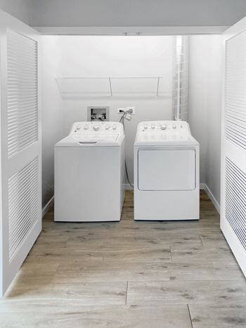 two washing machines in a laundry room with a wood floor