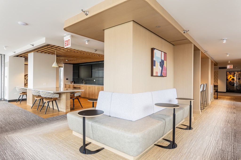 A white couch with a black metal base sits in a room with a wooden ceiling and a painting hanging on the wall at Kingsbury Plaza, Chicago, 60654