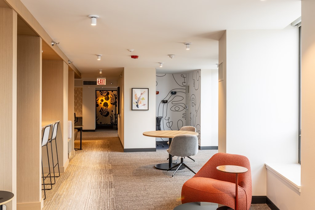 A hallway with a red chair and a white wall at Kingsbury Plaza, Chicago, IL, 60654