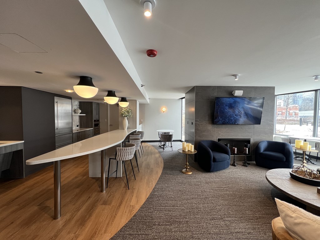 A modern living room with a curved wooden table and a television mounted on the wall at Kingsbury Plaza, Chicago