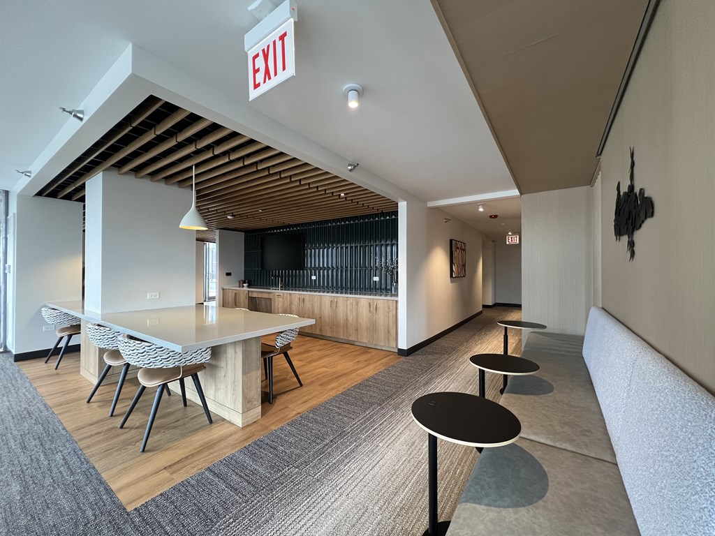 A room with a long table and chairs, a couch, and an exit sign at Kingsbury Plaza, Chicago, IL, 60654