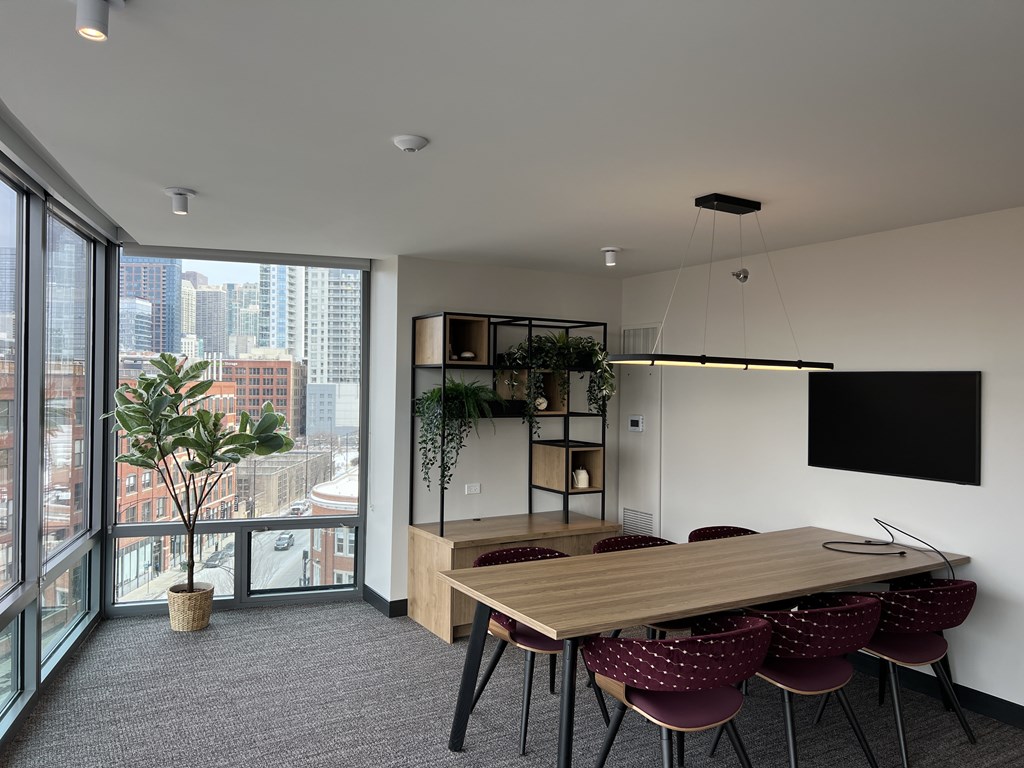 A conference room with a long table and chairs, a flat screen TV, and a view of the city outside the window at Kingsbury Plaza, Chicago, 60654