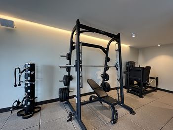 A black weight bench with a barbell on it in a room at Kingsbury Plaza Apartments, Chicago, IL