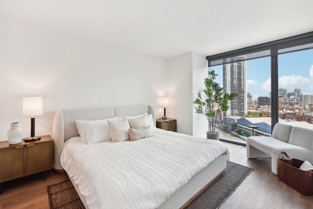 a white bedroom with a large bed and a view of the city at Cassidy on Canal, Chicago, IL, 60654