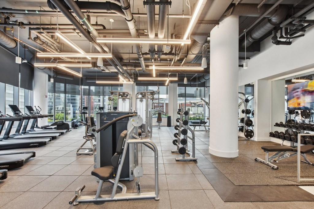 a gym with weights and other exercise equipment in a building with large windows at Cassidy on Canal, Chicago