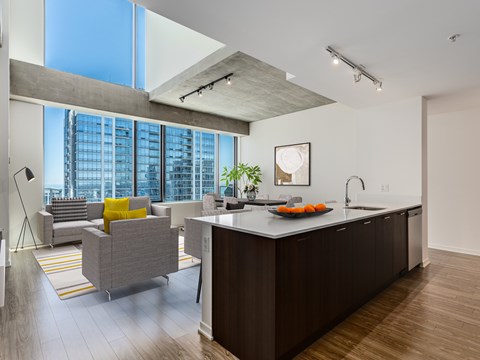 A modern kitchen with a large island and a living area with a couch and a chair.