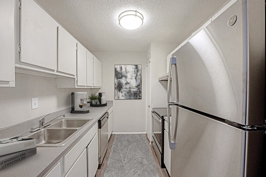 Galley style kitchen with white cabinets and stainless steel appliances  at The Waverly, Belleville, Michigan
