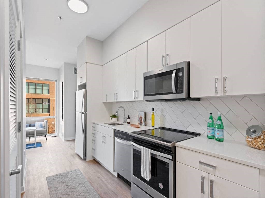 A modern kitchen with white cabinets and a black countertop.