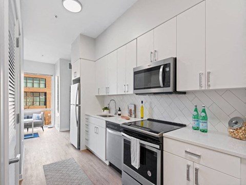 A modern kitchen with white cabinets and a black countertop.