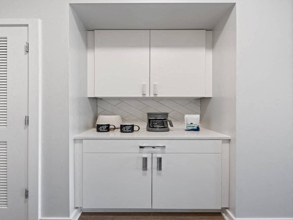 A white cabinet with a coffee maker and glasses on top.