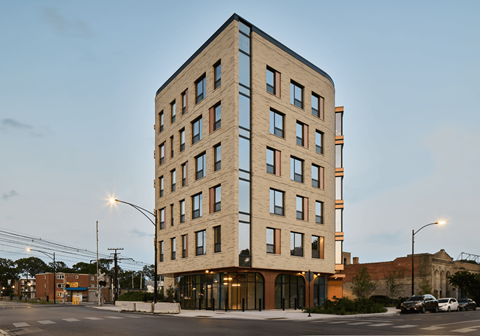 A tall building with a flat roof and many windows is shown.