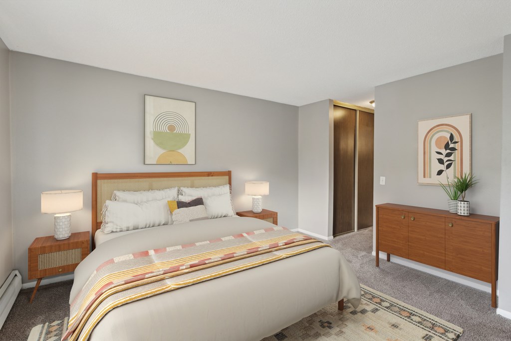 A bedroom with a large bed, a nightstand with a lamp, and a wooden dresser.