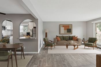 A living room with a grey couch, a wooden coffee table, and a painting on the wall.