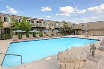 A large swimming pool surrounded by wooden chairs and umbrellas.