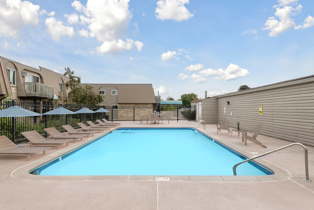 A large outdoor swimming pool surrounded by sun loungers and umbrellas.