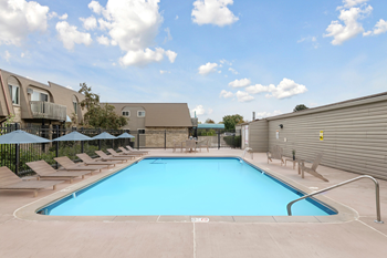 A large outdoor swimming pool surrounded by sun loungers and umbrellas.