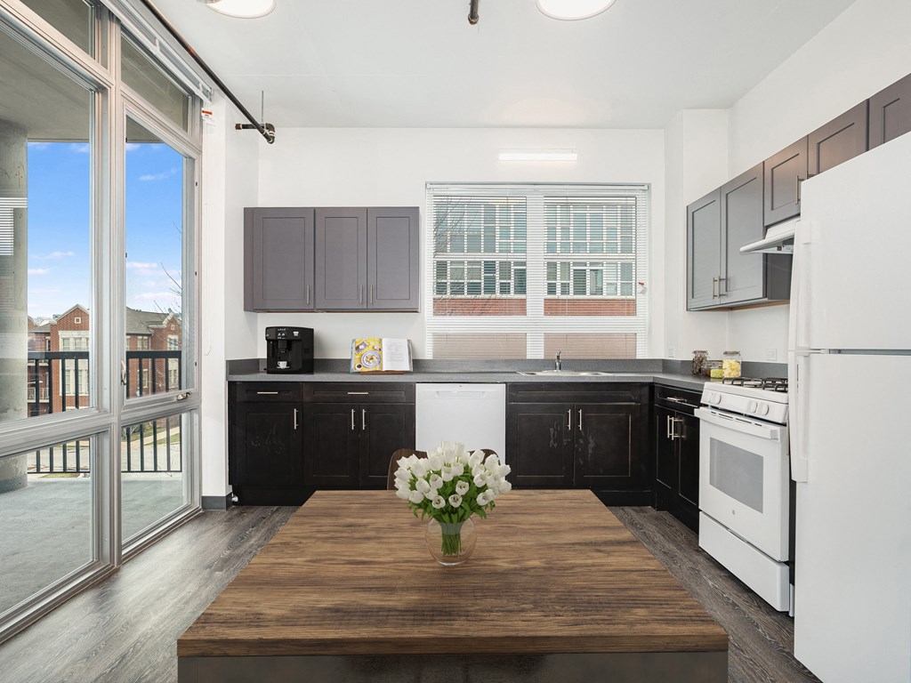 a kitchen with black cabinets and white appliances and a wooden table