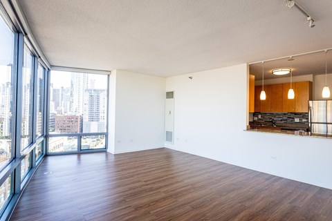 A large empty room with wooden floors and a view of the city through large windows.