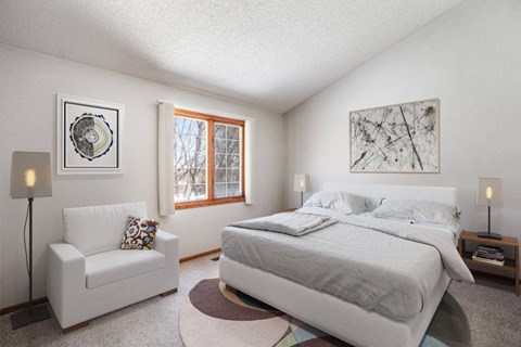 a bedroom with a bed and a chair and a window at Seasons Villas, Woodbury, MN