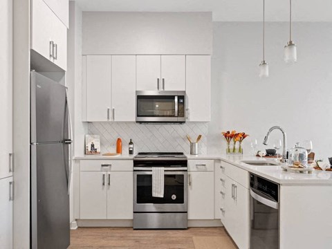 A modern kitchen with a refrigerator on the left and a stove top oven in the center.
