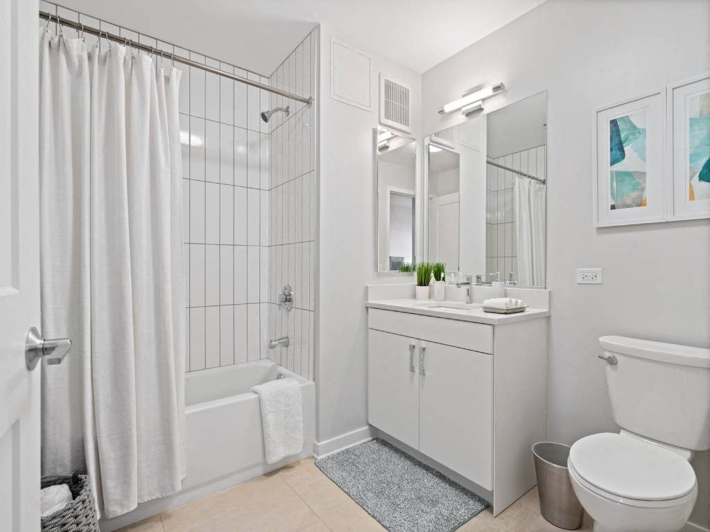 A white bathroom with a shower curtain and a towel hanging on the door.
