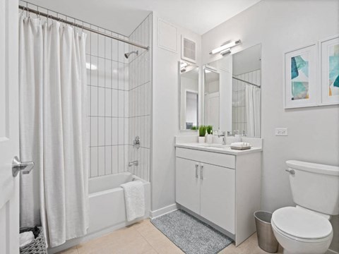 A white bathroom with a shower curtain and a towel hanging on the door.