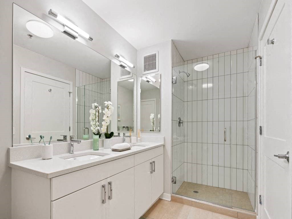 A white bathroom with a sink, mirror, and shower.
