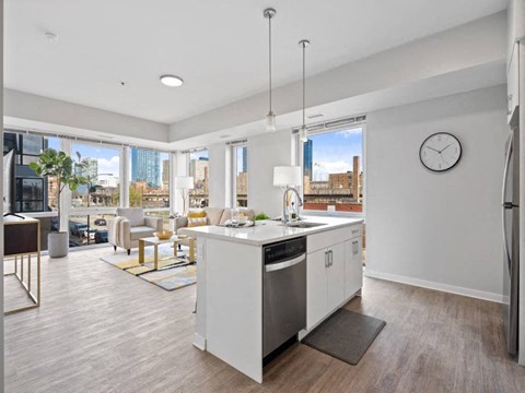 A modern kitchen with white appliances and a large window overlooking the city.