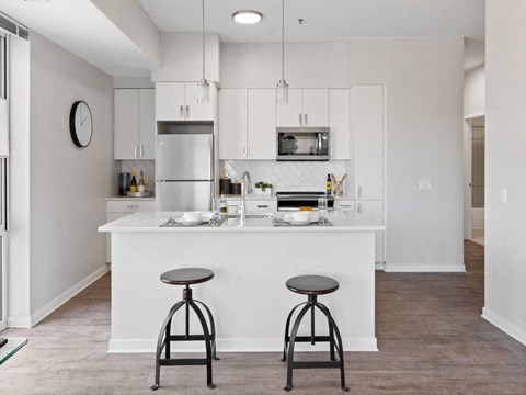 A kitchen with a white counter and two black stools.