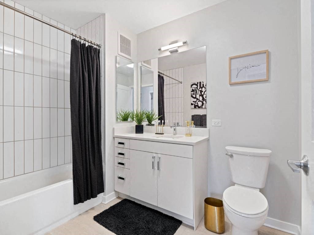 A white bathroom with a black and white tiled shower.