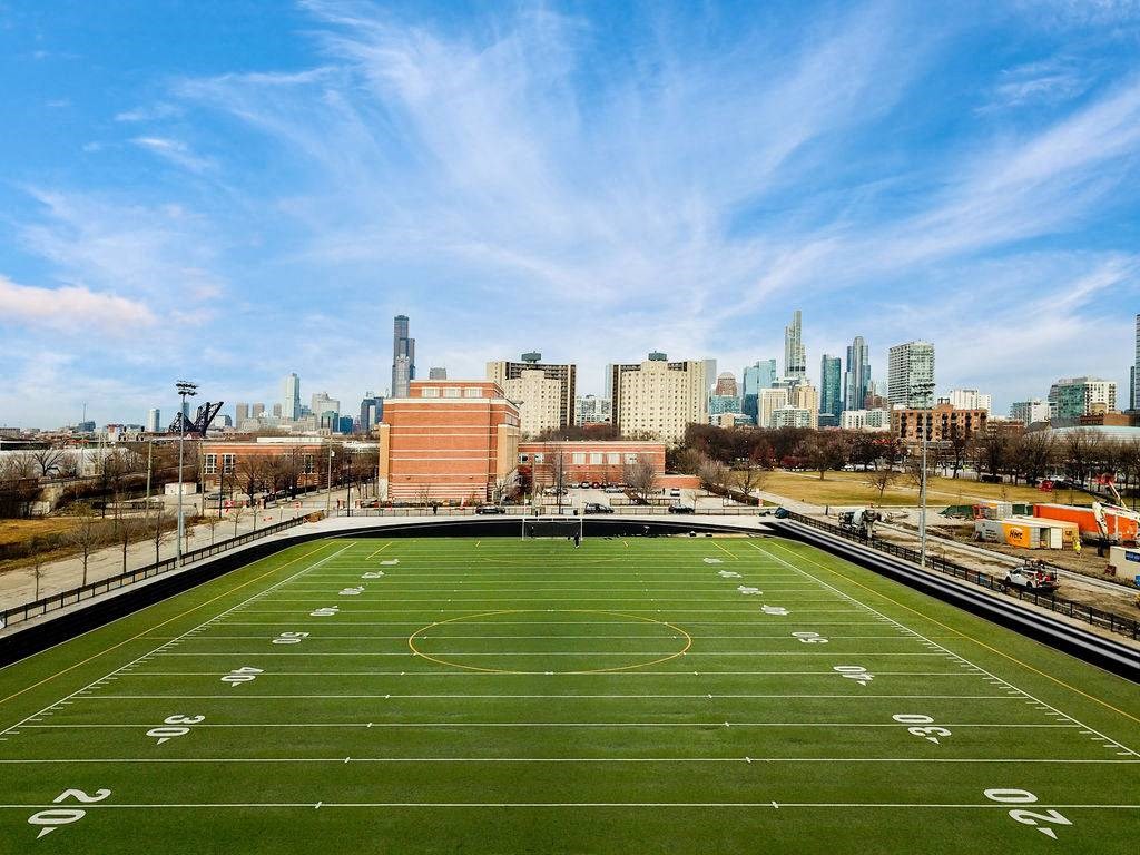 A football field with numbers on it and a city skyline in the background.