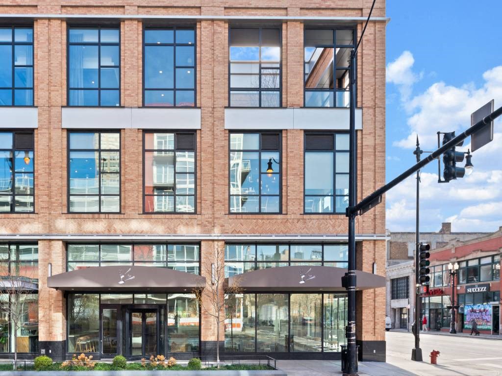 A modern building with a glass facade and a black awning.
