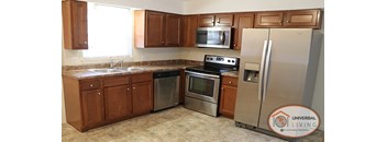 A kitchen with wooden cabinets and a stainless steel refrigerator.