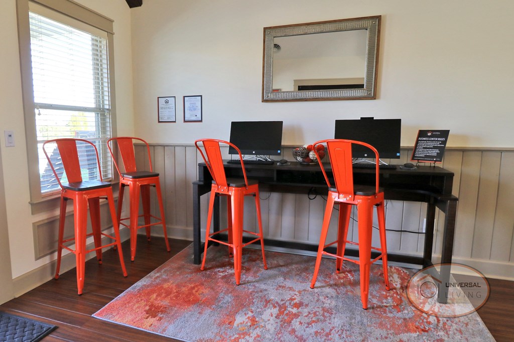 A business center with orange chairs, computers with free Wi-Fi.