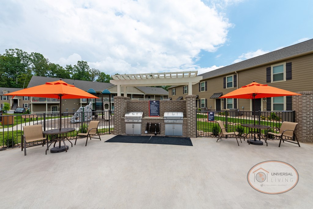 a patio with tables and umbrellas and a grill in front of a building