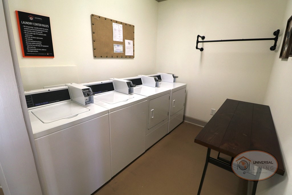 A laundry center with multiple stacked washer and dryers, and a table.