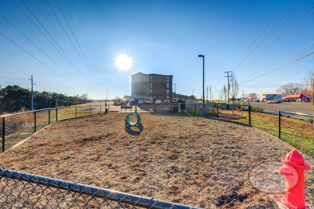 A dog park with seating, water station for pets, pet waste pick-up station, and obstacles for your dog to play on.