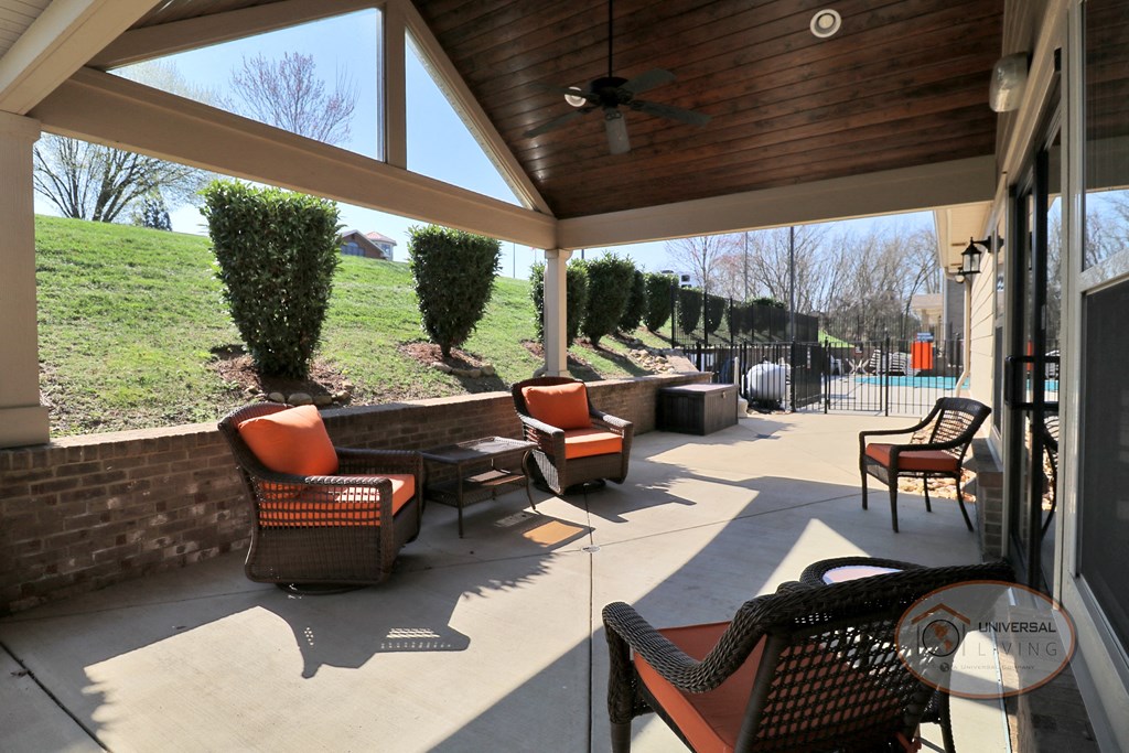 A covered patio with lounge chairs and a table.