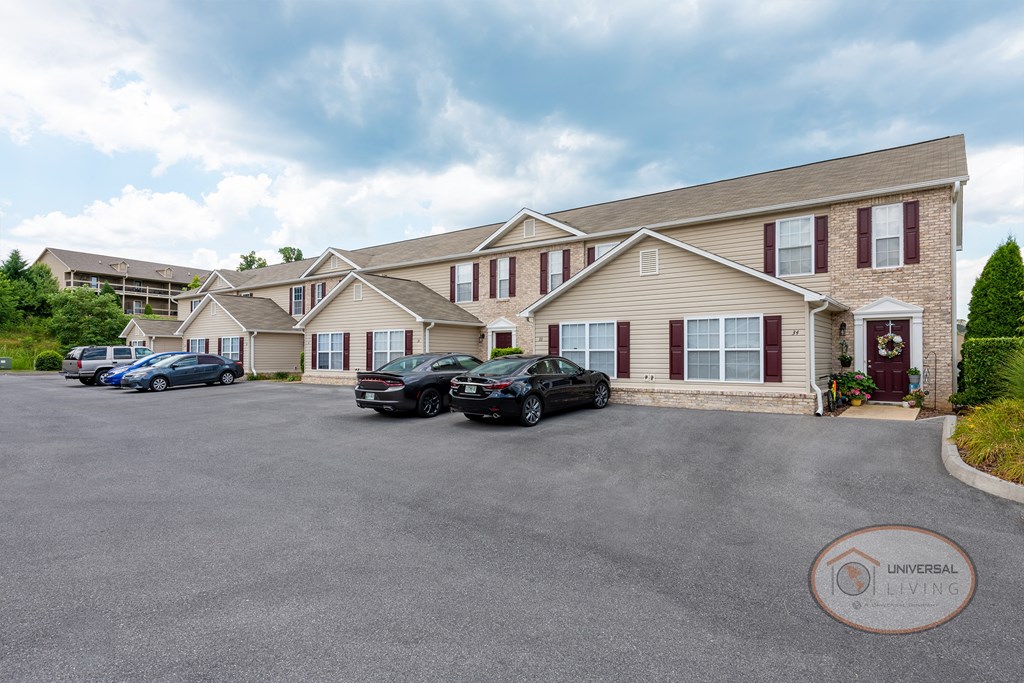 A large stone and tan apartment home with maroon shutters and doors.