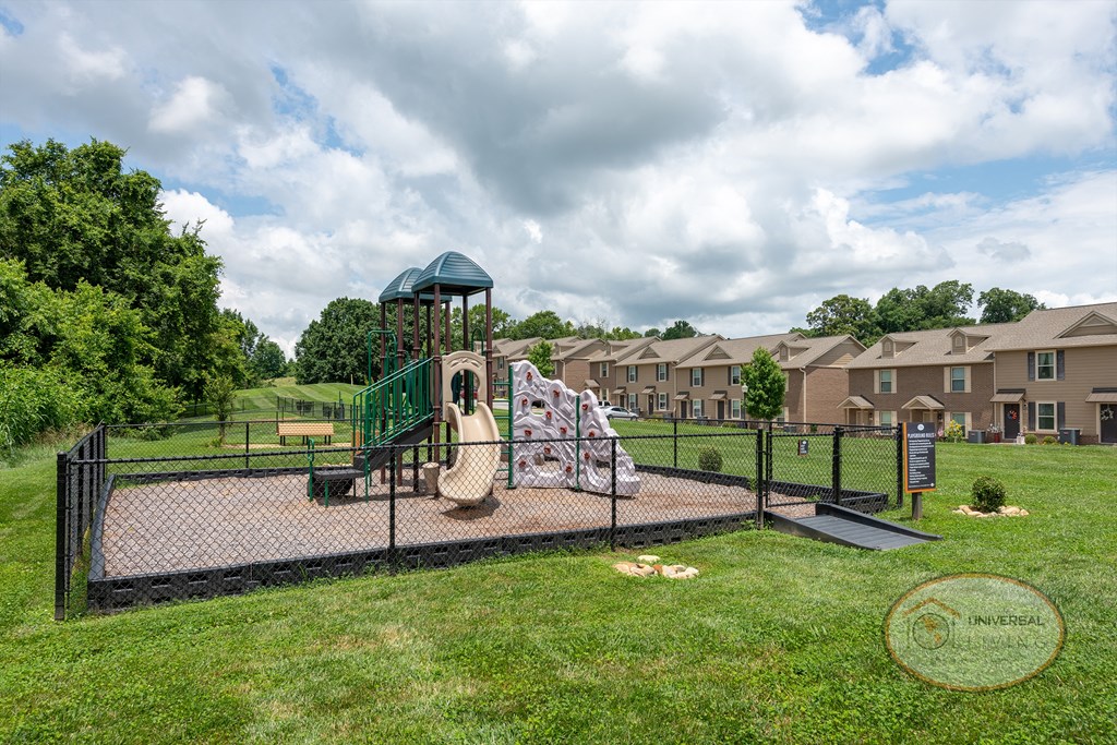 A fenced-in playground with a jungle gym and a slide.