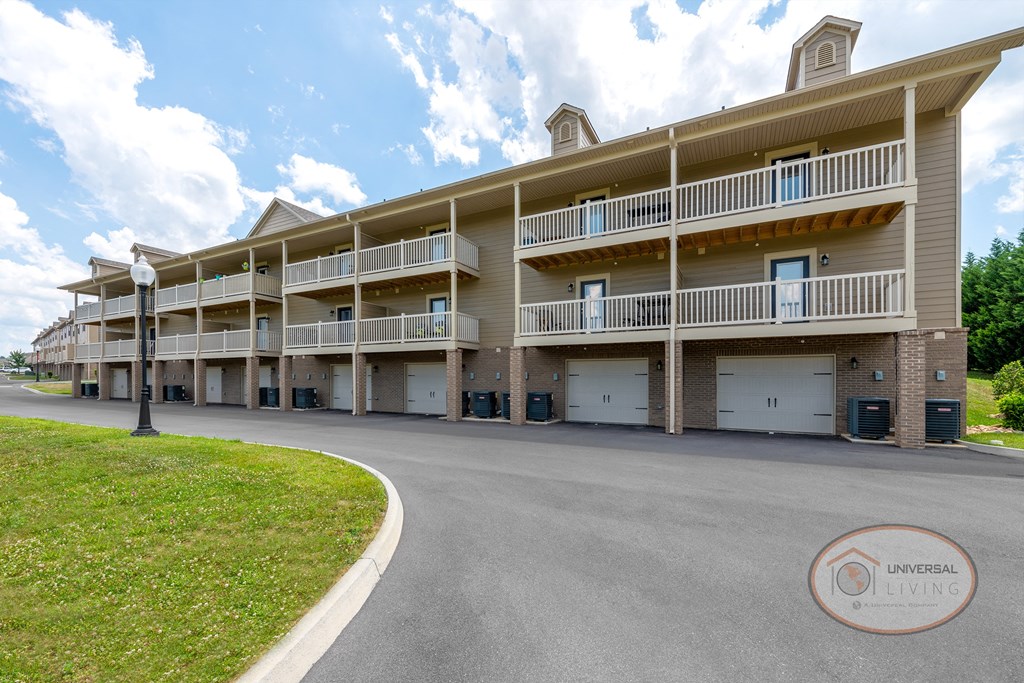 One Bedroom Stacked Apartment Homes from the rear with tan siding, balconies and garages.