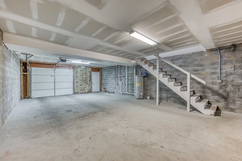 A spacious basement with a staircase and a garage door.