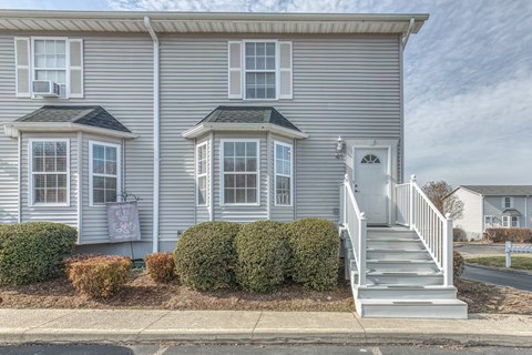 A two-story house with a grey exterior and a white door.