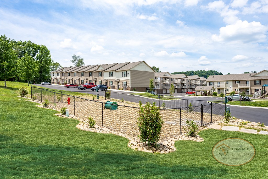 a view of a fenced in park with apartments in the background