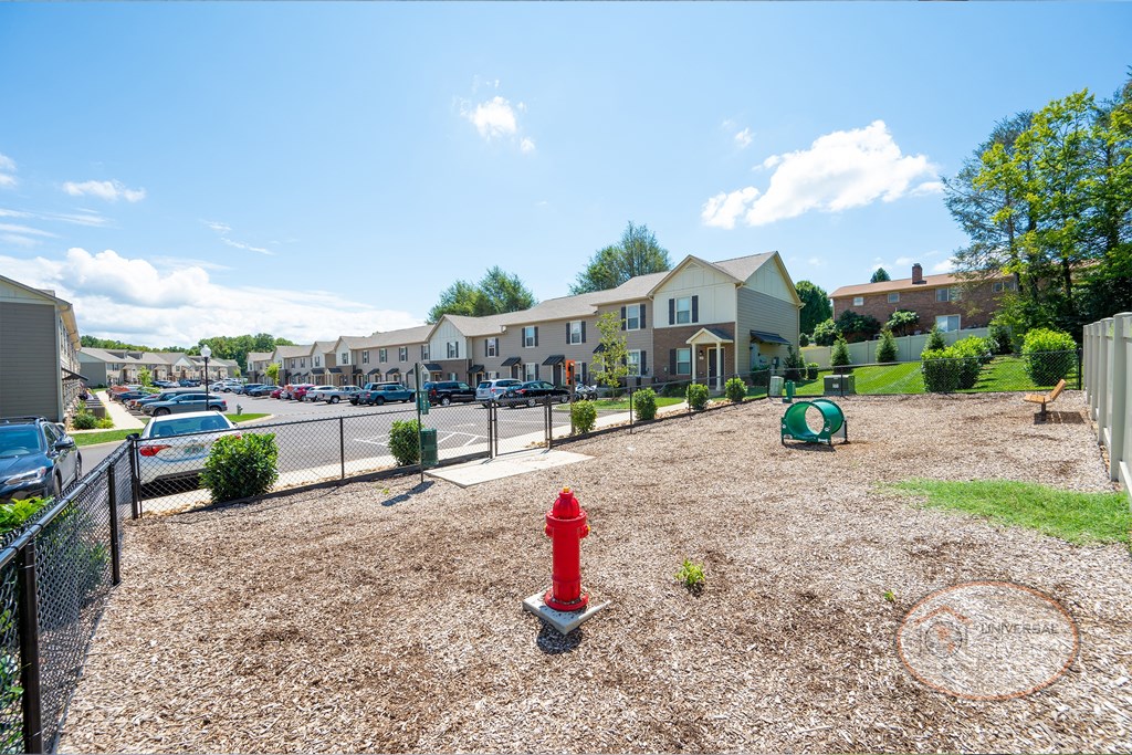 a parking lot with a red fire hydrant in front of some apartments