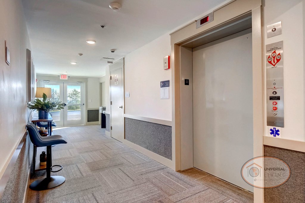 Carpeted entrance hallway with elevators and seating area.