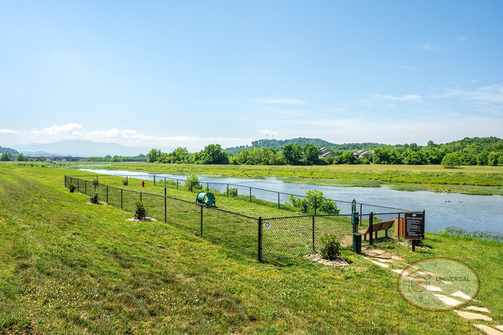 A fenced-in dog park complete wit seating, overlooking the river.